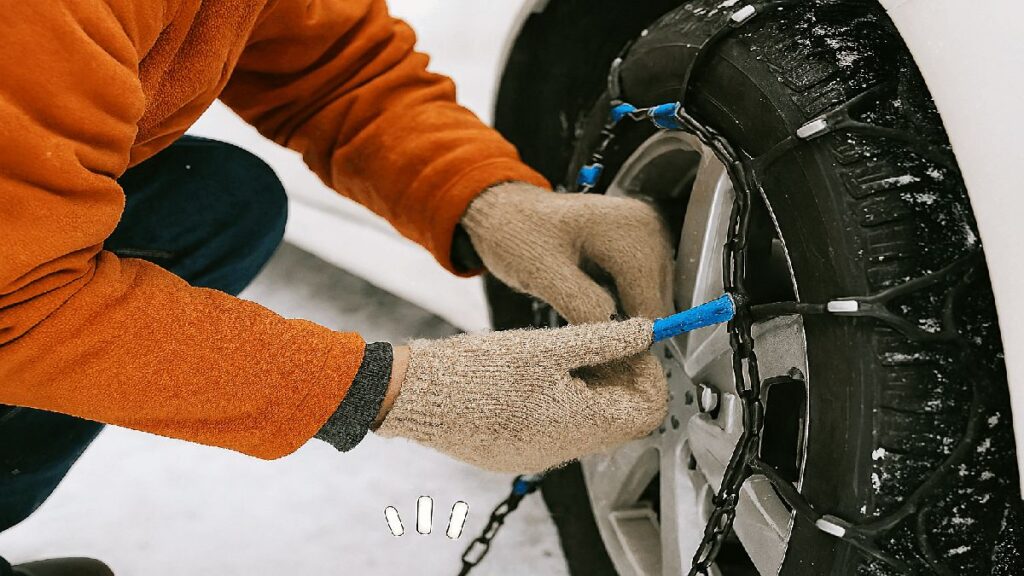 非金属製タイヤチェーンを右ハンドル車のタイヤに装着している途中の手元のクローズアップ