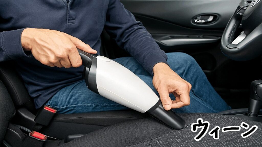 ハンディクリーナーでシートの隙間を掃除する男性の手元と車内の様子